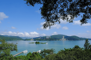 Scenic view of Sun Moon Lake in Taiwan, with boats on the blue water and green mountains in the background.